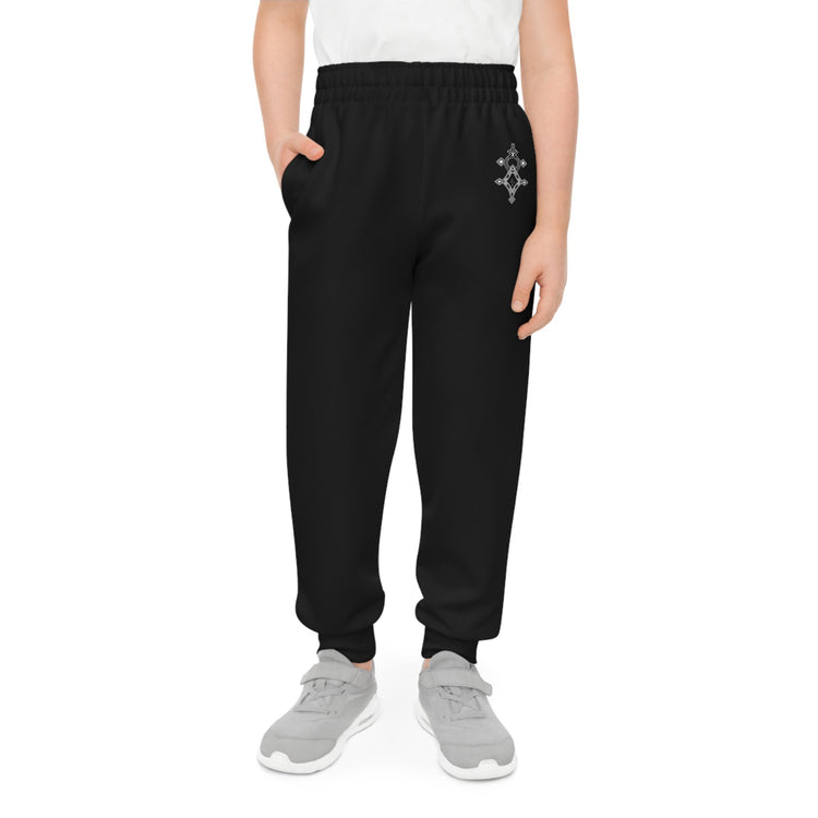 Black boys joggers with elastic waistband and side pockets, made from recycled polyester and spandex, modeled by a child wearing gray sneakers.