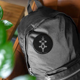 Round pin with geometric design attached to black backpack, durable steel and glossy finish accessory