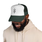 Man wearing white and green trucker cap with adjustable snapback and embroidered front design
