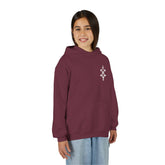 Girl wearing maroon Girls Heavy Blend Hooded Sweatshirt with kangaroo pocket and embroidery design
