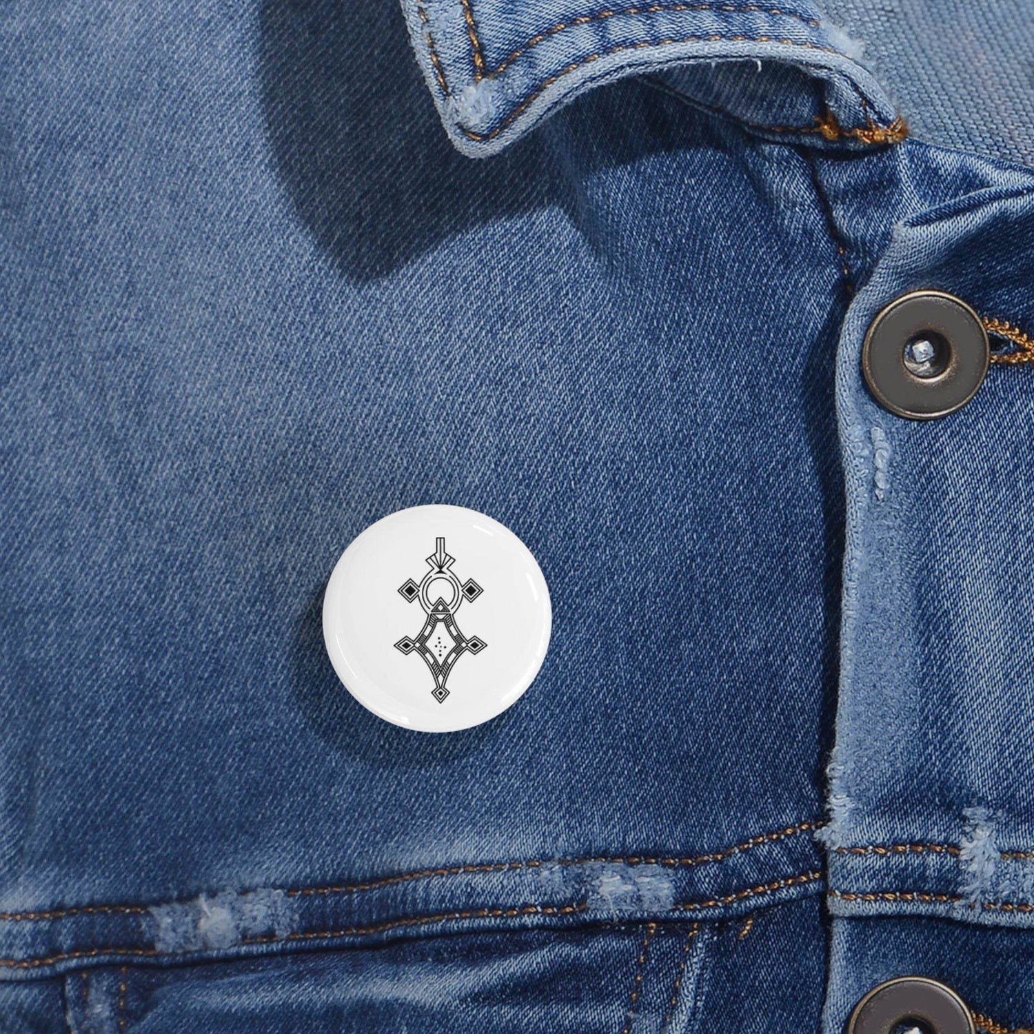 Round pin with black geometric design on denim jacket, steel shell and glossy scratch-resistant mylar cover, magnetic backing