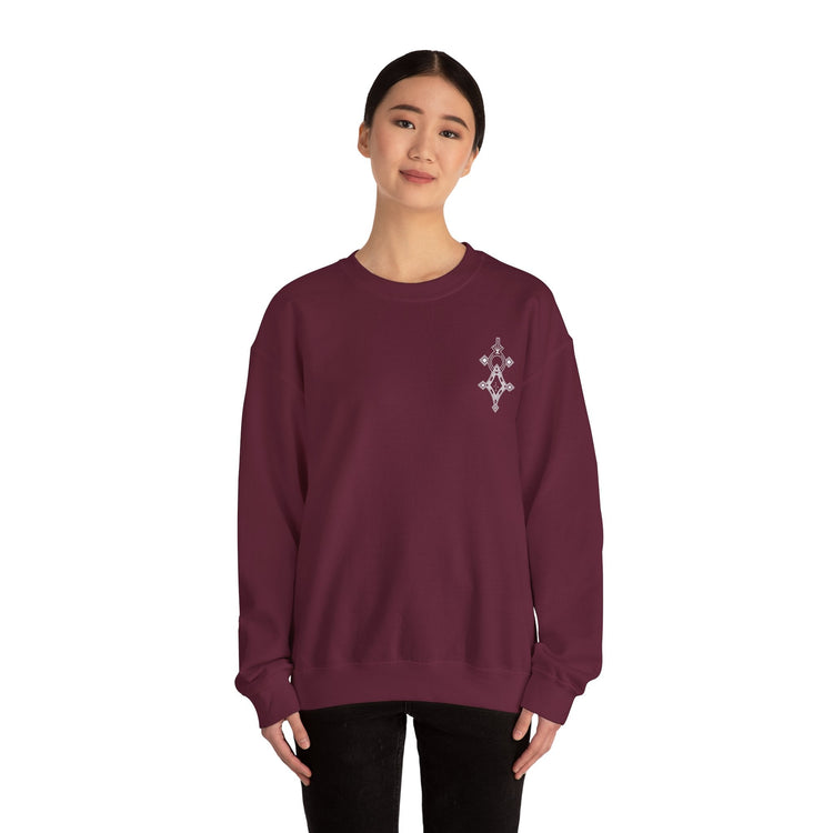 Woman wearing maroon Heavy Blend™ crewneck sweatshirt with embroidery on chest, made of cotton and polyester blend.
