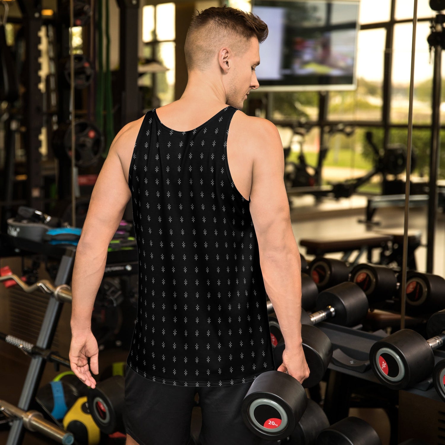 Man wearing black unisex tank top with subtle pattern working out in gym holding dumbbells