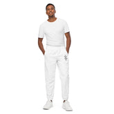 Man wearing white men track pants with elastic ankle cuffs and white sneakers standing against white background