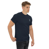 Man wearing navy blue classic tee with small chest design and black jeans