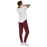Man wearing burgundy men fleece sweatpants with elastic waistband and cuffed legs, paired with white sneakers and a white t-shirt, shown from the back.