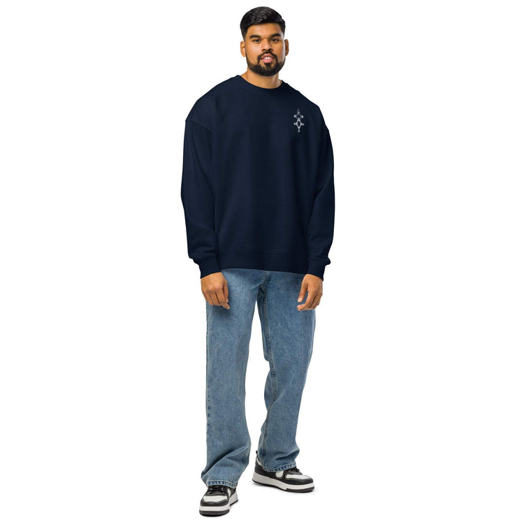 Man wearing navy organic oversized sweatshirt with blue jeans and sneakers standing against white background