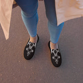 Women’s stylish black slip-on canvas shoes with white geometric design and rubber soles worn with blue jeans