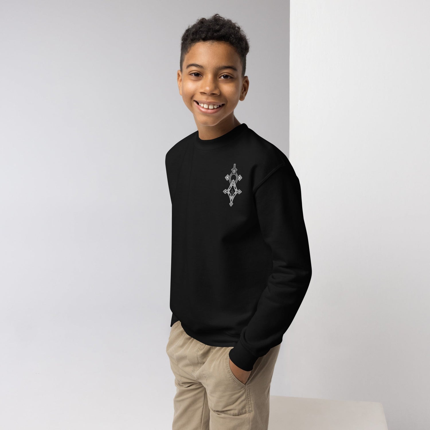 Youth crewneck sweatshirt in black with graphic design worn by smiling boy with hands in pockets
