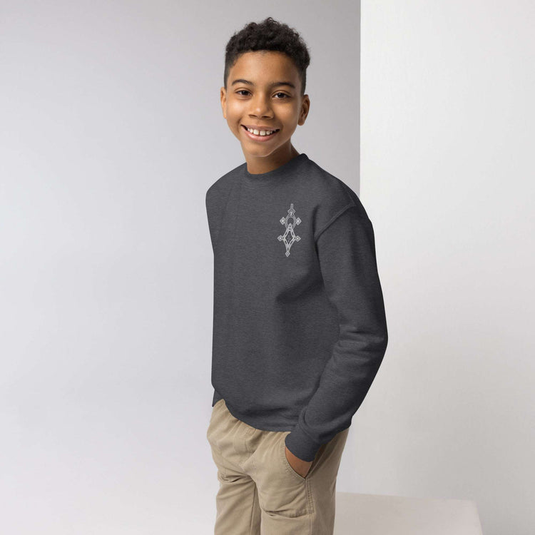 Youth wearing a dark gray cozy crewneck sweatshirt with a small chest design, paired with beige pants