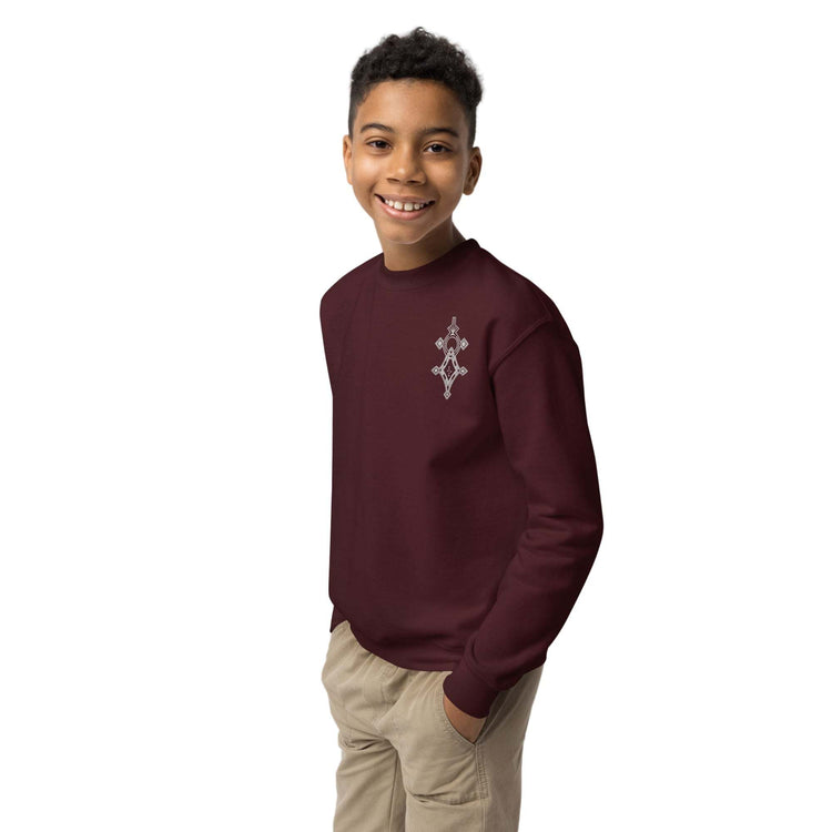 Youth wearing maroon crewneck sweatshirt with small white design, casual youth crewneck sweatshirt in fleece fabric