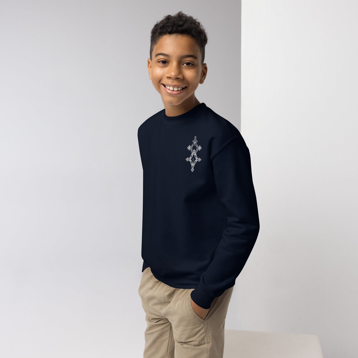 Youth wearing navy blue crewneck sweatshirt with graphic design, smiling and standing with hands in pockets