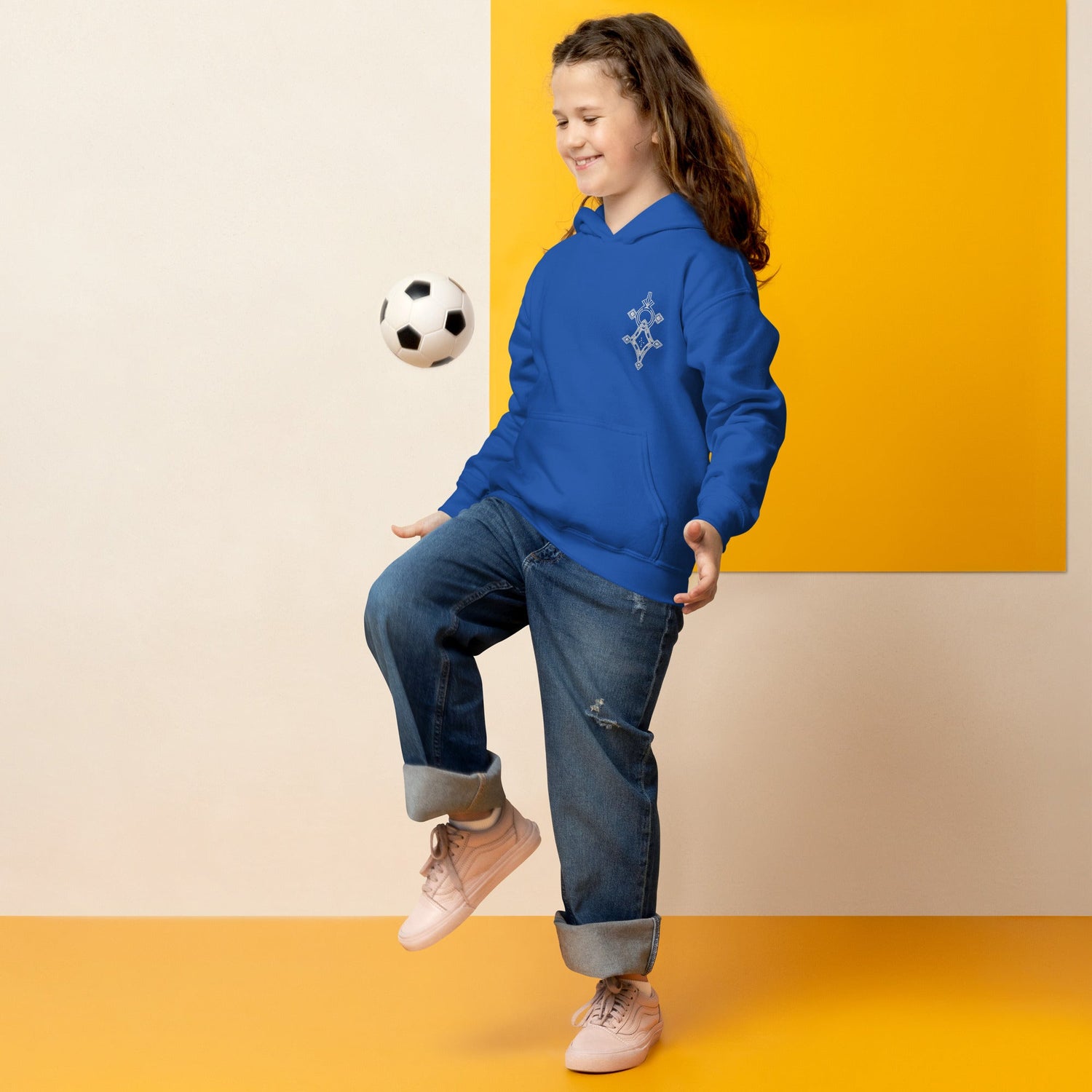 Child wearing blue youth heavy blend hoodie playing with soccer ball indoors