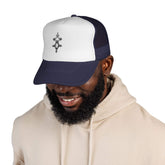Man wearing a navy and white trucker cap with adjustable snapback and embroidered front logo