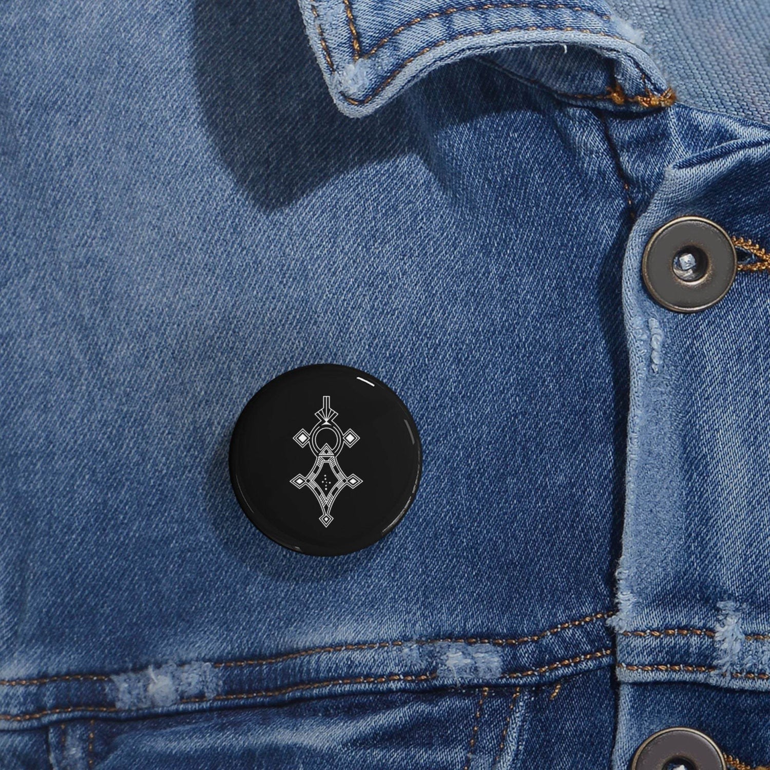 Black round pin with geometric design on blue denim jacket, steel shell and magnetic backing, scratch-resistant glossy finish
