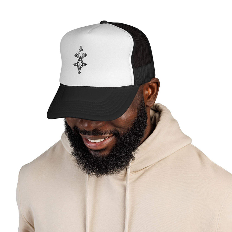 Black and white trucker cap with mesh back and adjustable snap closure worn by a smiling man