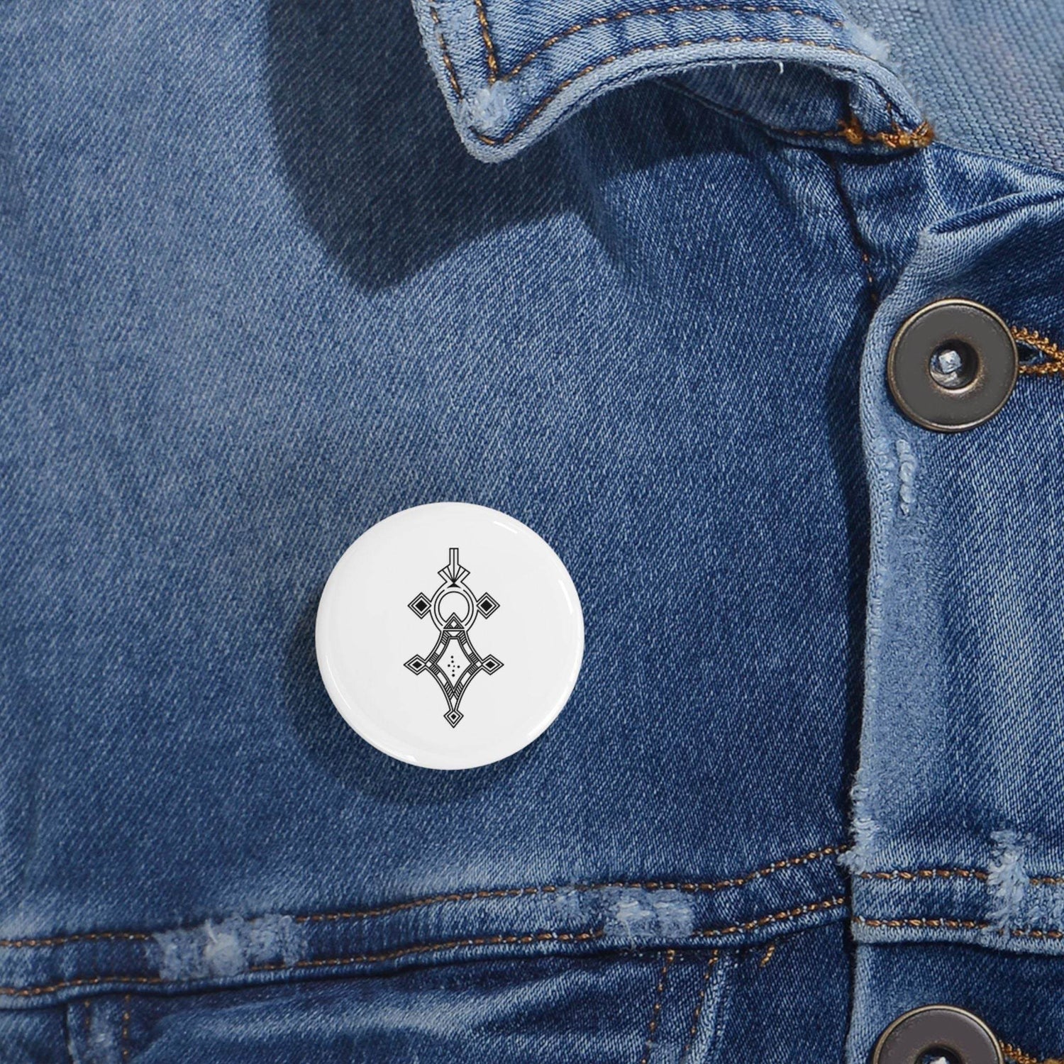 White round pin with black geometric design on blue denim jacket, magnetic metal backing, scratch-resistant glossy finish