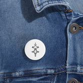 White round pin with black geometric design on blue denim jacket, magnetic metal backing, scratch-resistant glossy finish