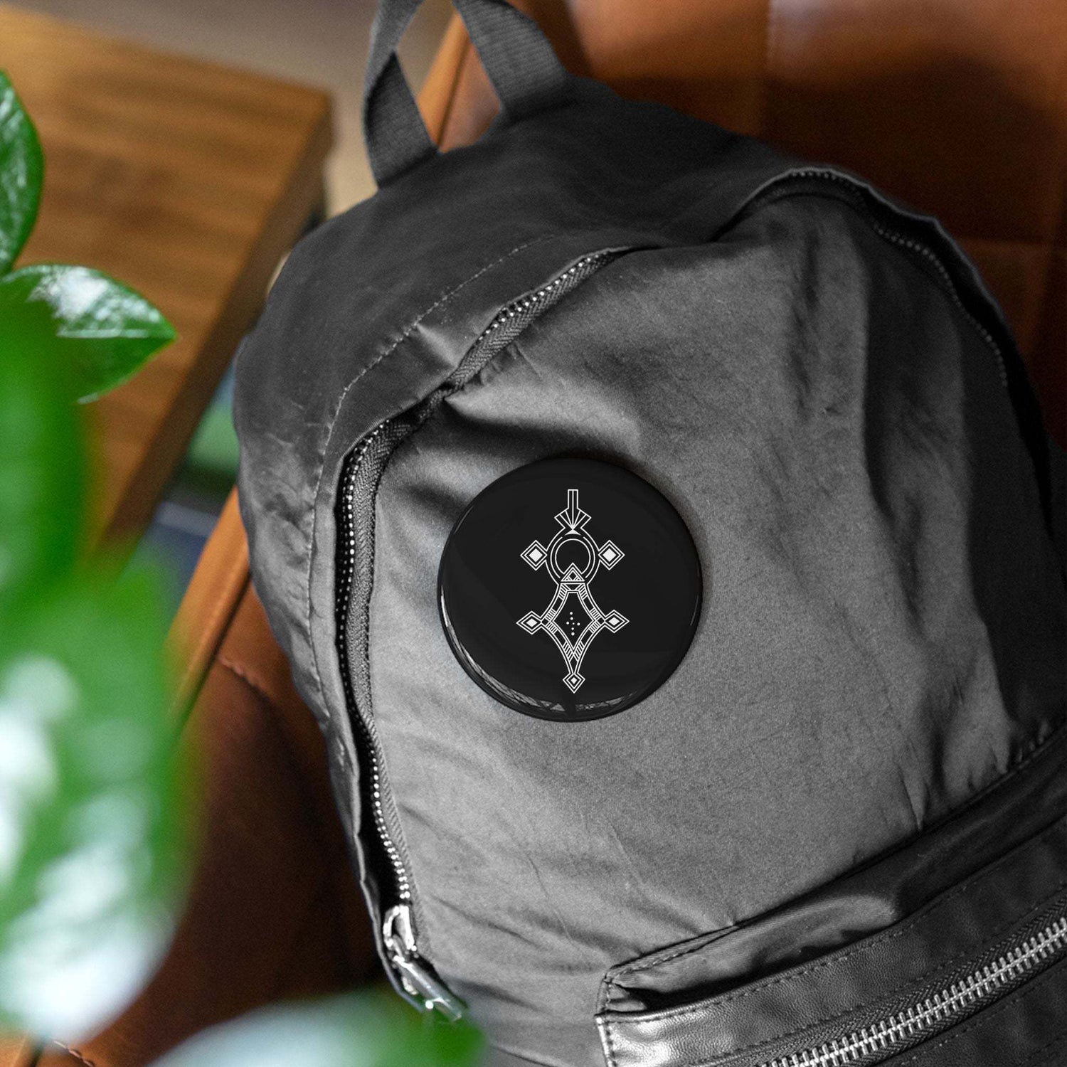 Black round pin with geometric design on black backpack, scratch-resistant glossy finish round pins with steel shell and mylar cover