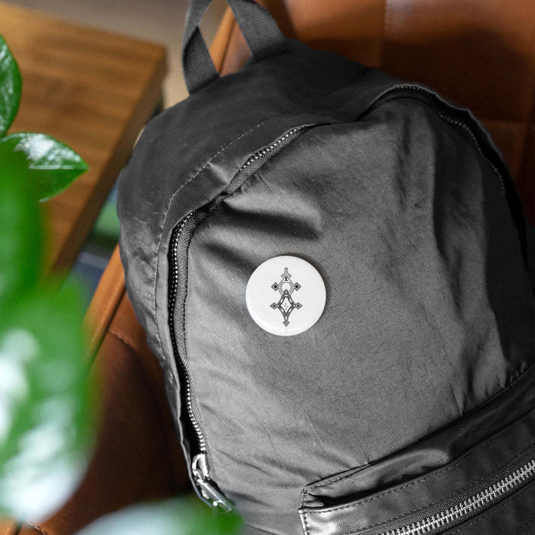 Black backpack with a white round pin featuring a geometric design with magnetic backing and scratch-resistant glossy finish