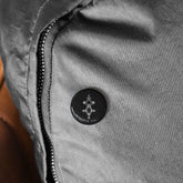 Black round pin with geometric design on gray fabric jacket, magnetic backing, scratch-resistant glossy finish, durable UV cover.