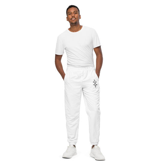Man wearing white men track pants with elastic ankle cuffs and white sneakers standing against white background