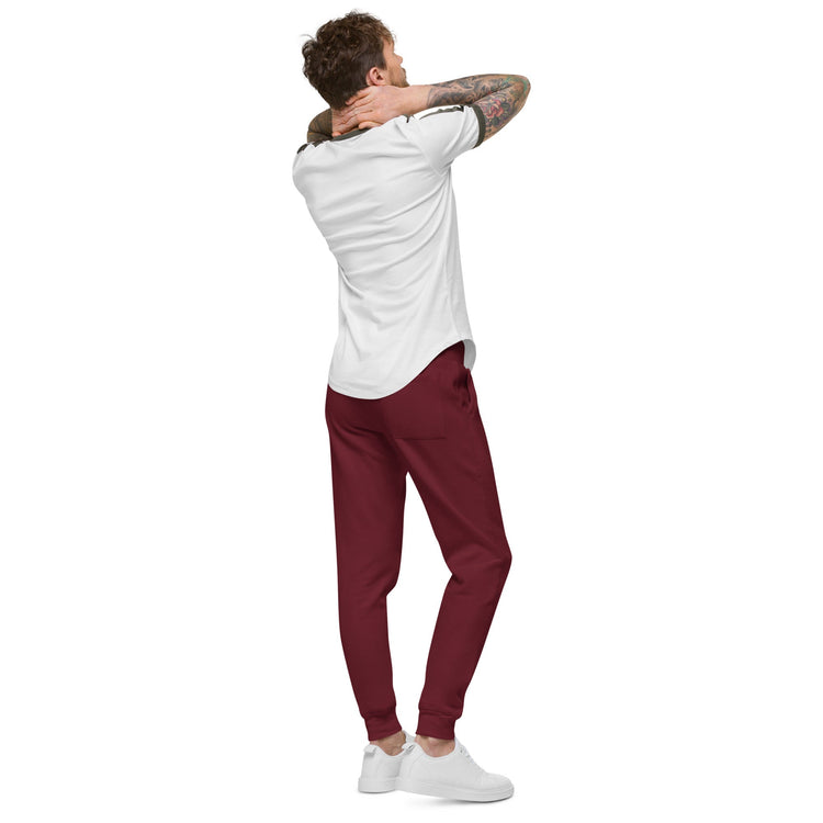 Man wearing burgundy men fleece sweatpants with elastic waistband and cuffed legs, paired with white sneakers and a white t-shirt, shown from the back.