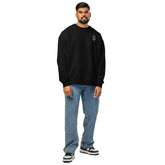 man wearing black organic oversized sweatshirt with jeans and sneakers standing against white background