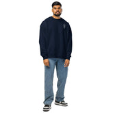 Man wearing navy organic oversized sweatshirt with blue jeans and sneakers standing against white background