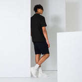 Rear view of man wearing black men polo shirt with shorts and white sneakers in minimalist setting