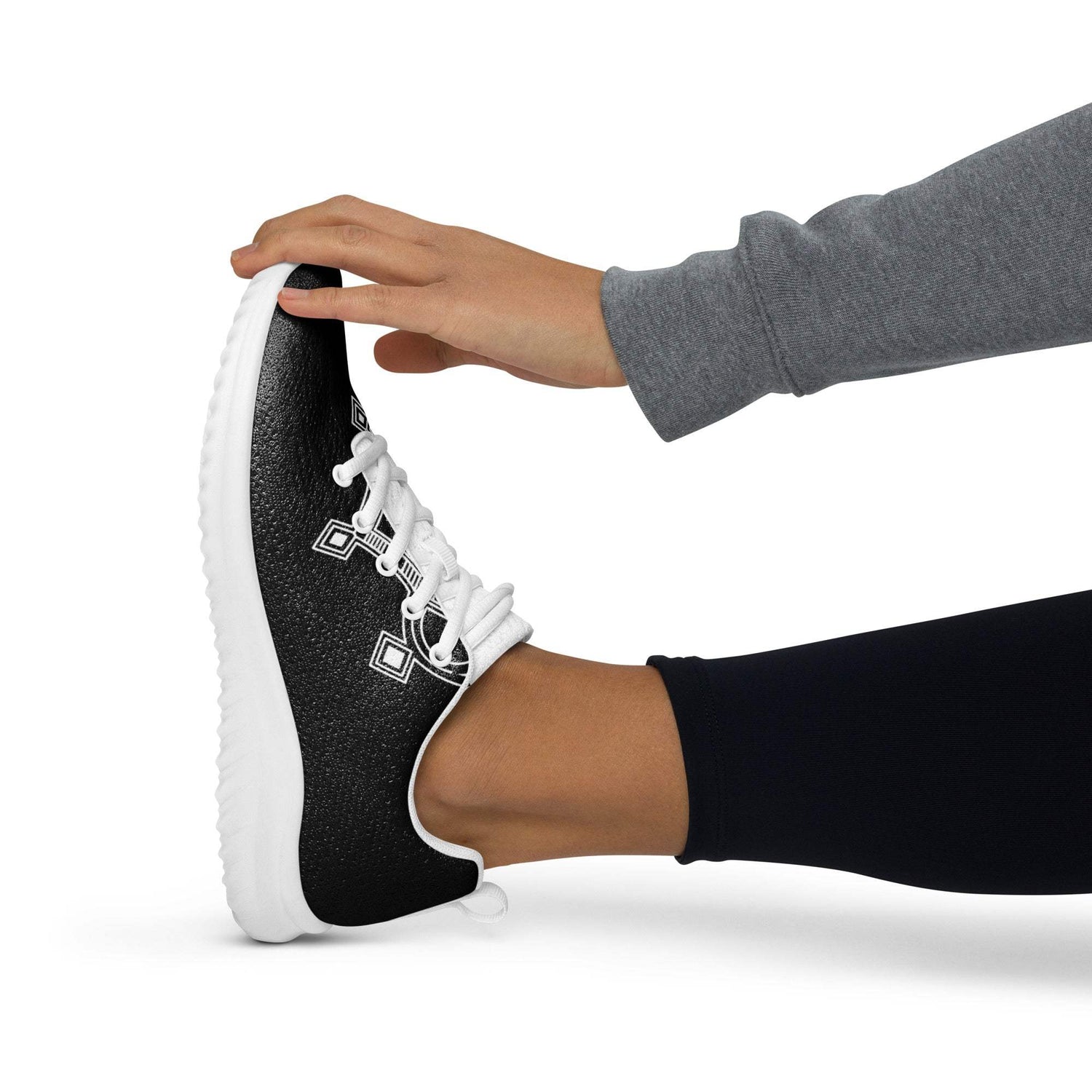 Black women’s athletic shoe with white laces and rubber outsole being worn during foot stretch