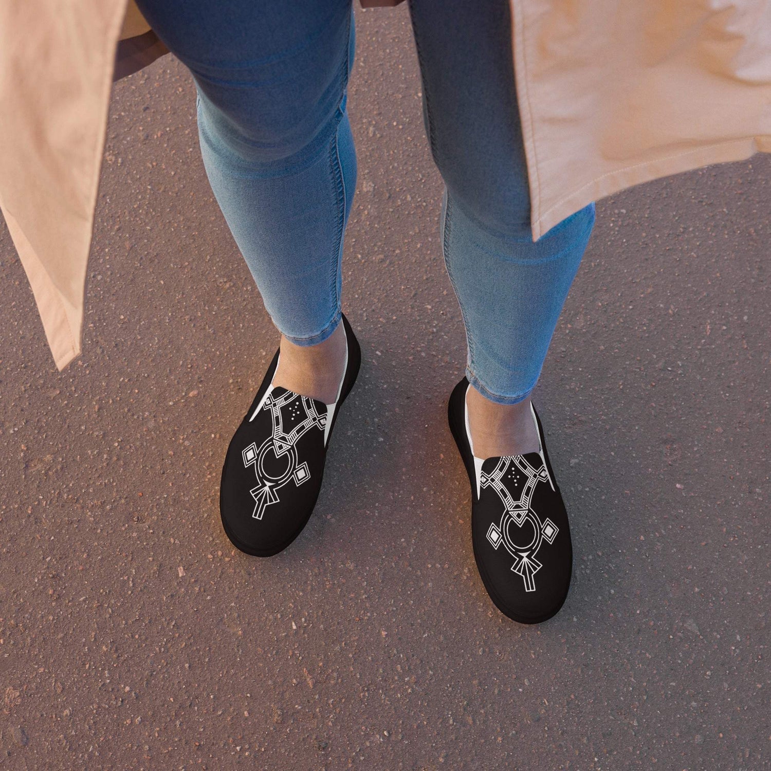 Women’s stylish black slip-on canvas shoes with white geometric design and rubber soles worn with blue jeans