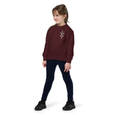 Youth crewneck sweatshirt in maroon worn by child with geometric design on chest